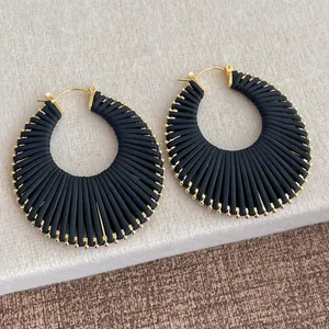 Vue détaillée de boucles d'oreilles noires tissées en éventail avec perles dorées