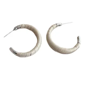 Boucles d'oreilles créoles en C argentées avec cuir crème texturé croco sur fond blanc