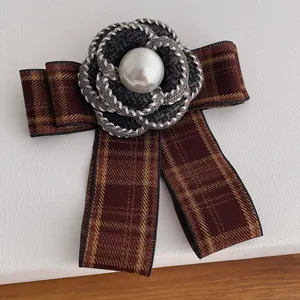 Elegant camellia brooch with tweed petals and pearl center on a brown plaid ribbon