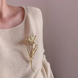 Elegant gold tulip brooch with petal texture pinned on a stylish cream knit sweater