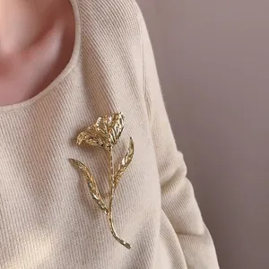 Vintage golden tulip brooch with hammered texture pinned on a beige ribbed sweater