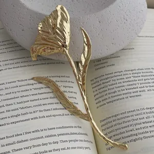 Detail of golden tulip brooch with hammered metal texture resting on an open book