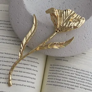 Vintage golden metal tulip flower brooch with textured petals on a classic book backdrop