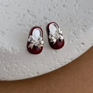 Macro-opname van rode emaille Mary Jane schoen oorbellen met zilveren strik en kristal