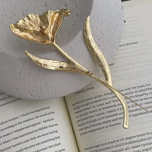 Detail of a large gold tulip flower brooch with textured petals and dual pin fasteners