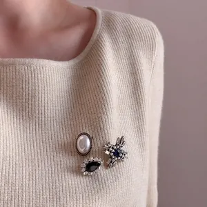 Vintage brooch set featuring pearls, black gemstones, and a cross star pin on fabric