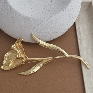 Macro shot of gold tulip brooch with metallic texture and elegant curved petals