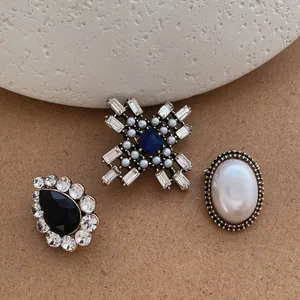 Detailed view of vintage cross brooches with pearls and rhinestones on stone textures