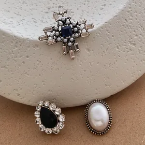 Detail of vintage Baroque brooches with blue crystals, black gems, and pearls on a stand
