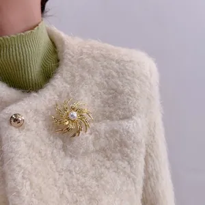Close-up of golden spiral firework brooch with pearl on white faux fur jacket