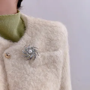 Elegant silver spiral fireworks brooch with pearl on beige coat lapel for women