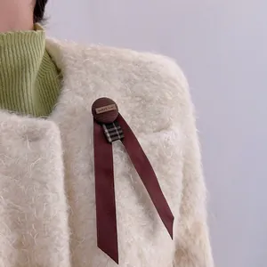 Detail of a vintage coffee brown bow brooch with houndstooth ribbon and sweet love label