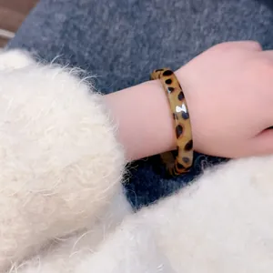 Close-up of vintage leopard print resin bangle on a soft white fluffy sweater sleeve