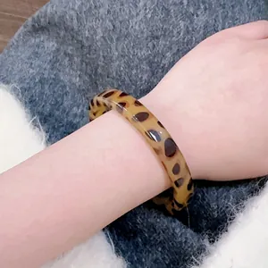 Close-up of a wide resin leopard print bangle with a polished finish on a model's wrist