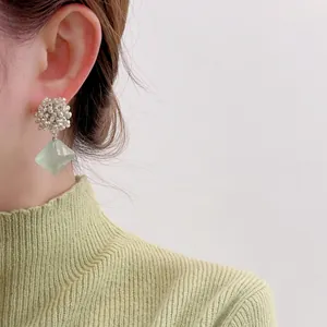 Beaded silver studs with light green faceted stone pendant shown on a model