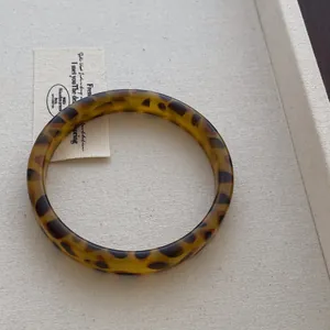 Macro shot of wide resin bangle with amber leopard pattern on minimalist display tray