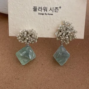 Detail view of silver beaded stud earrings with a green fluorite gemstone pendant