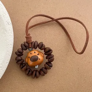 Close-up of wooden puppy pendant with coffee bean ring and brown leather strap