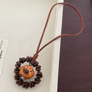 Detail of handcrafted wooden puppy pendant with coffee bean ring and leather strap