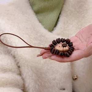 Detailed close-up of a wooden lion keychain featuring coffee bean mane on a leather strap