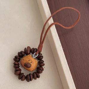 Detailed view of peach wood cartoon animal pendant with roasted coffee beans and suede strap