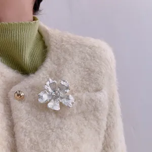 Elegante spilla a fiore argento con pietra di cristallo su una giacca bianca donna