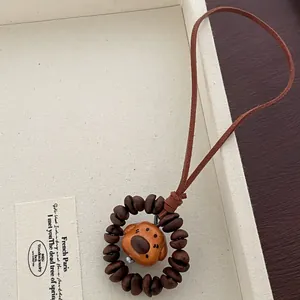 Detail of wooden puppy pendant with coffee bean beads and brown suede cord accessory