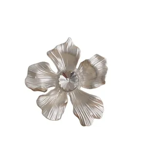 Elegante spilla a fiore argento con trama in metallo spazzolato e cristallo centrale