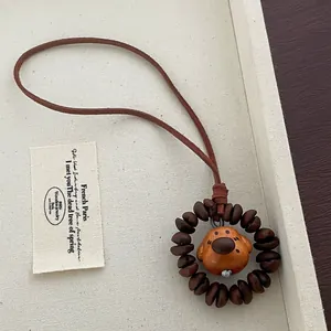 Detailed view of handcrafted peach wood puppy charm with coffee bean beads and leather cord
