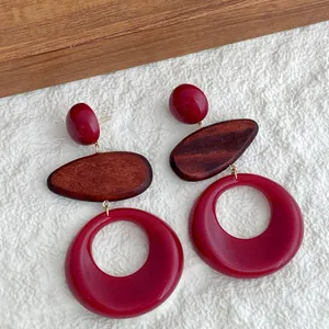 Detalle macro de pendientes de resina rojo vino y madera natural de estilo vintage