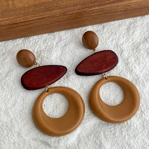 Detalle de pendientes vintage de madera y resina sobre una tela blanca texturizada