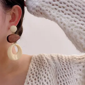 Detalle de pendientes retro geométricos con aros de resina crema y toques de madera