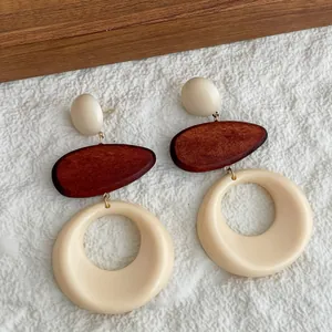 Detalle de pendientes bohemios de madera y resina con diseño geométrico de gota