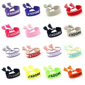 Dettaglio macro di sedici braccialetti jacquard colorati con ricamo J'ADORE
