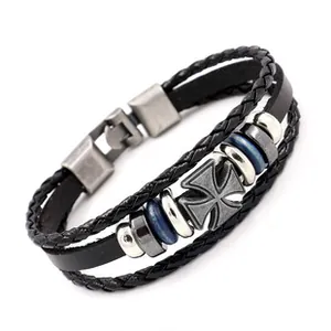 Detail eines mehrlagigen Lederarmbands mit Vintage-Metallkreuz und blauen Perlen