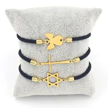 Detalle de pulseras de cuerda negra con colgantes dorados de ángel, cruz y hexagrama