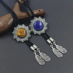Dettaglio di cravatte bolo vintage con pendenti a raggiera turchese e piume metalliche