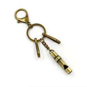 Close-up of vintage bronze whistle pendant with decorative engraving on lobster clasp
