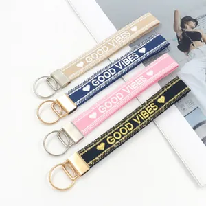 Détail de quatre bracelets porte-clés tissés colorés avec broderie GOOD VIBES