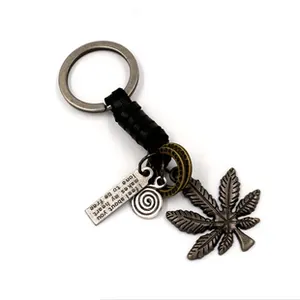 Detail of punk leather keychain with metal leaf charm and engraved rectangular tag
