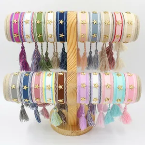 Detailed view of woven geometric bracelets with golden star charms and colorful tassels