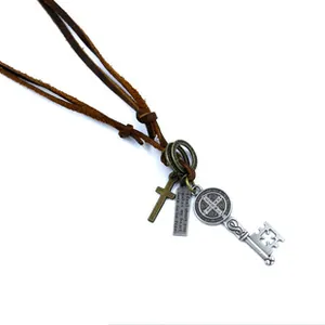 Detail of vintage leather necklace with bronze cross, key, and engraved metal plate