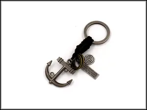 Detail of vintage zinc alloy anchor keychain with nautical tag and braided rope cord