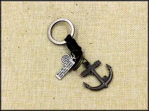 Macro detail of nautical anchor keychain with engraved plate and leather braided ring