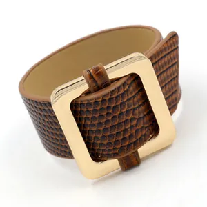 Macro detail of dark brown snakeskin faux leather bracelet with golden square metal buckle