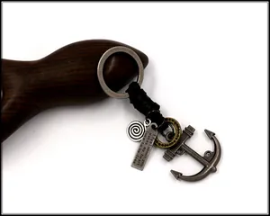Close-up of vintage anchor keychain with engraved metal tag on premium wooden prop