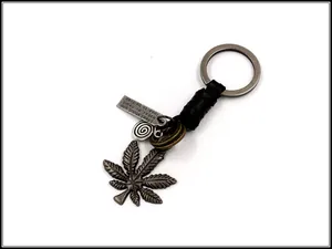 Macro view of vintage alloy leaf pendant and engraved metal plate on braided leather keychain
