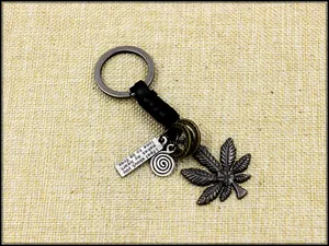 Detail of vintage maple leaf pendant and engraved plaque on a woven leather keychain