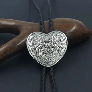 Dettaglio del bolo tie a cuore con incisioni floreali e cordino in pelle nera intrecciata
