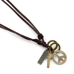 Vintage bronze peace sign and cross pendant necklace with brown leather cord on white background